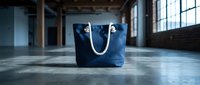 Navy canvas tote bag with rope handles displayed on concrete floor in industrial loft space with natural light, suitable for fashion, retail, and lifestyle design projects.