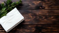 Fresh green dill sprigs and white paper napkins on dark rustic wooden background with natural grain pattern texture, top view with copy space.