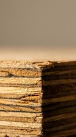 Stack of weathered wooden planks with rough textured edges and natural grain patterns on neutral background for construction and carpentry projects.