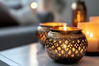 Glowing ornate metal candle holders with burning candles creating cozy atmosphere. Decorative lattice pattern casts romantic shadows in evening light.