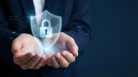 Businessman hands protecting glowing cybersecurity shield with padlock icon against digital circuit board background for data protection and privacy.