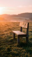 Weathered wooden chair sitting alone in vast rural field during golden hour sunset with distant mountains and warm atmospheric lighting.
