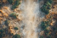 Aerial view of misty mountain terrain with orange rocky cliffs and green vegetation creating dramatic natural patterns in morning fog. Wilderness landscape.