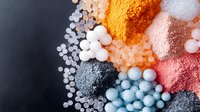Colorful collection of various bath salts, beads, and cosmetic powders arranged on dark background for spa and beauty treatments.