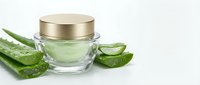 Natural aloe vera gel in glass jar with golden lid surrounded by fresh cut aloe leaves on white background for skincare and cosmetic products.