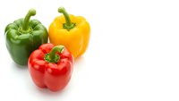 Fresh colorful bell peppers in red yellow and green isolated on white background for healthy cooking and nutrition concepts.