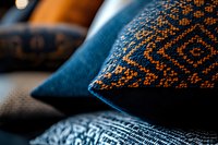 Decorative cushions with intricate ethnic pattern in navy blue and orange colors on sofa, close-up view showing detailed textile ornamental design.