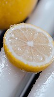 Fresh cut lemon half with water droplets in macro photography showing detailed pulp segments and citrus texture on light background. Perfect for food styling.
