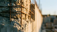 Weathered stone wall with metal grid casting shadows in golden sunlight, suitable for architectural backgrounds, texture overlays, and design projects.