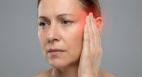 Middle-aged Caucasian woman touching temple experiencing headache or migraine pain with red highlighted area showing discomfort and stress relief concept.