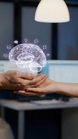 Hands holding glowing brain hologram with innovation icons representing artificial intelligence, mental health, neuroscience and cognitive technology concepts.