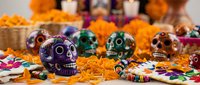Colorful decorated sugar skulls with marigold flowers and candles for Day of the Dead celebration. Traditional Mexican Dia de los Muertos altar decoration setup.