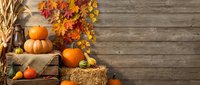 Autumn harvest display with pumpkins, gourds, wheat stalks and colorful fall leaves arranged on rustic wooden background for seasonal decorating and thanksgiving.