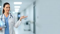 Female doctor in white coat presenting with open hand gesture in modern hospital corridor for medical presentations and healthcare marketing.