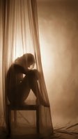 Silhouetted figure sitting on chair by window with sheer curtains, expressing sadness, loneliness, depression, mental health struggle, emotional distress, introspection, solitude, despair, anxiety, grief, isolation.