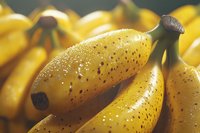 Fresh ripe yellow bananas with natural brown spots and speckles on peel, macro close-up view showing natural texture and ripeness pattern in soft light.