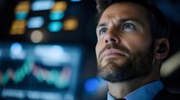 Mature male professional with dark beard and blue eyes wearing business attire, looking upward thoughtfully in modern office environment with blurred financial data displays. Stock photo for corporate, finance, leadership, and business concepts.