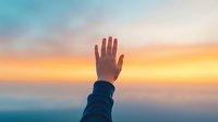 Hand reaching towards vibrant sunset sky with orange and turquoise clouds, symbolizing hope, freedom, achievement and spiritual connection. Atmospheric dreamy mood.