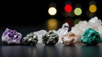 Collection of natural mineral specimens including amethyst, pyrite, quartz and malachite crystals arranged on dark surface with colorful bokeh lights.