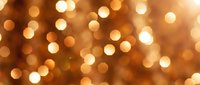 Golden bokeh lights background with warm glowing circles creating magical atmosphere for holiday celebrations and festive decorations.