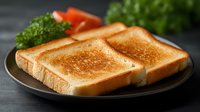 Crispy golden-brown toast slices on dark plate with fresh tomato and parsley garnish. Close-up view of breakfast setting against dark background. Food photography.