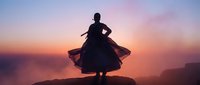 Woman silhouette dancing in flowing dress against dramatic sunset sky over ocean cliff creating peaceful moment of freedom and self-expression.