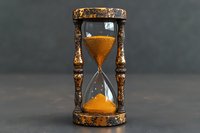 Vintage ornate hourglass with golden sand flowing through glass bulbs in decorative bronze frame against dark background for time management concepts.