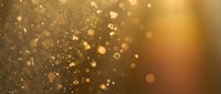 Golden bokeh lights with sparkling particles and warm glow creating magical atmosphere for luxury backgrounds and festive celebrations.