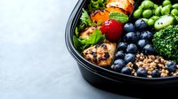 Fresh healthy meal prep bowl with grilled chicken, quinoa, blueberries, strawberry, broccoli and edamame beans on light background. Clean eating lunch.
