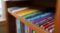 Colorful art markers arranged in rainbow order on wooden shelf, selective focus on vibrant pens creates artistic depth and perspective for creative design projects.
