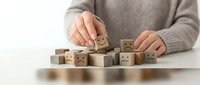 Person arranging wooden blocks with emoji faces showing different emotions for customer feedback rating and satisfaction survey concepts.