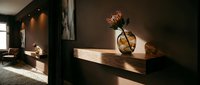 Wooden shelf with dried protea flower in glass vase against dark wall, modern minimalist interior design with warm lighting for home decor and styling.