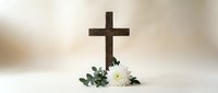Wooden cross with white chrysanthemum flowers on soft beige background for memorial services, funeral arrangements, and religious ceremonies.