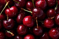 Fresh ripe cherries with water droplets, dark red and glossy, close-up view showing stems and natural texture for food photography.