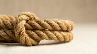 Natural jute rope with nautical knot on neutral background for marine crafts and rustic decor projects.