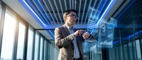 Professional businessman in glasses interacting with holographic digital interface in modern office with blue LED lighting and futuristic technology display.