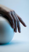Close-up of a hand resting on a light blue sphere against a neutral background, suitable for wellness, spa, and skincare marketing materials.