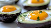 Creative breakfast presentation with eggs baked inside avocado halves, garnished with fresh herbs, macro food photography showing vibrant yolks and creamy texture.