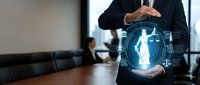 Professional businessman in dark suit protecting glowing digital human figure with hands in modern office boardroom representing HR management and employee care.