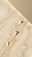 Cream marble stone surface with natural veining and carved linear grooves, showcasing luxury material texture for architectural and interior design projects.