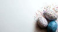 Speckled Easter eggs with colorful paint splatter effect on white background. Artistic holiday composition with decorative eggs and scattered dots.