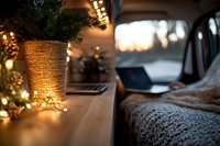 Cozy winter evening workspace with fairy lights, knitted blanket and potted plant on wooden desk, creating warm atmospheric home office setting at sunset.