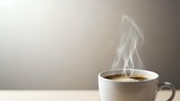 Hot steaming coffee cup on wooden table with warm beige background creating cozy morning atmosphere for cafe and beverage concepts.