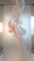 Elegant colorful smoke swirls rising gracefully in soft orange and blue tones against blurred interior background for creative design projects.