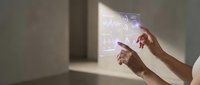 Hands interacting with futuristic holographic interface displaying digital data and graphics in modern minimalist interior space for technology presentations.