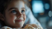 Young blonde girl with blue eyes smiling while eating breakfast pastry in cozy morning light with bokeh background for family lifestyle content.
