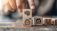 Wooden blocks with brain and hand icons representing emotional intelligence and soft skills concept on textured surface in muted tones.