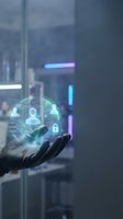 Hand holding digital holographic interface with user profiles, security icons, and data network visualization in modern office environment with neon lighting.