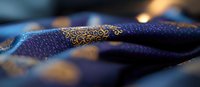 Luxurious navy blue silk fabric with intricate golden oriental pattern and embroidery details in soft focus, creating elegant textile background for fashion design.