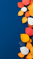 Colorful autumn leaves border on deep blue background. Orange, white, and coral paper cut foliage creates seasonal frame with copy space for text or design.